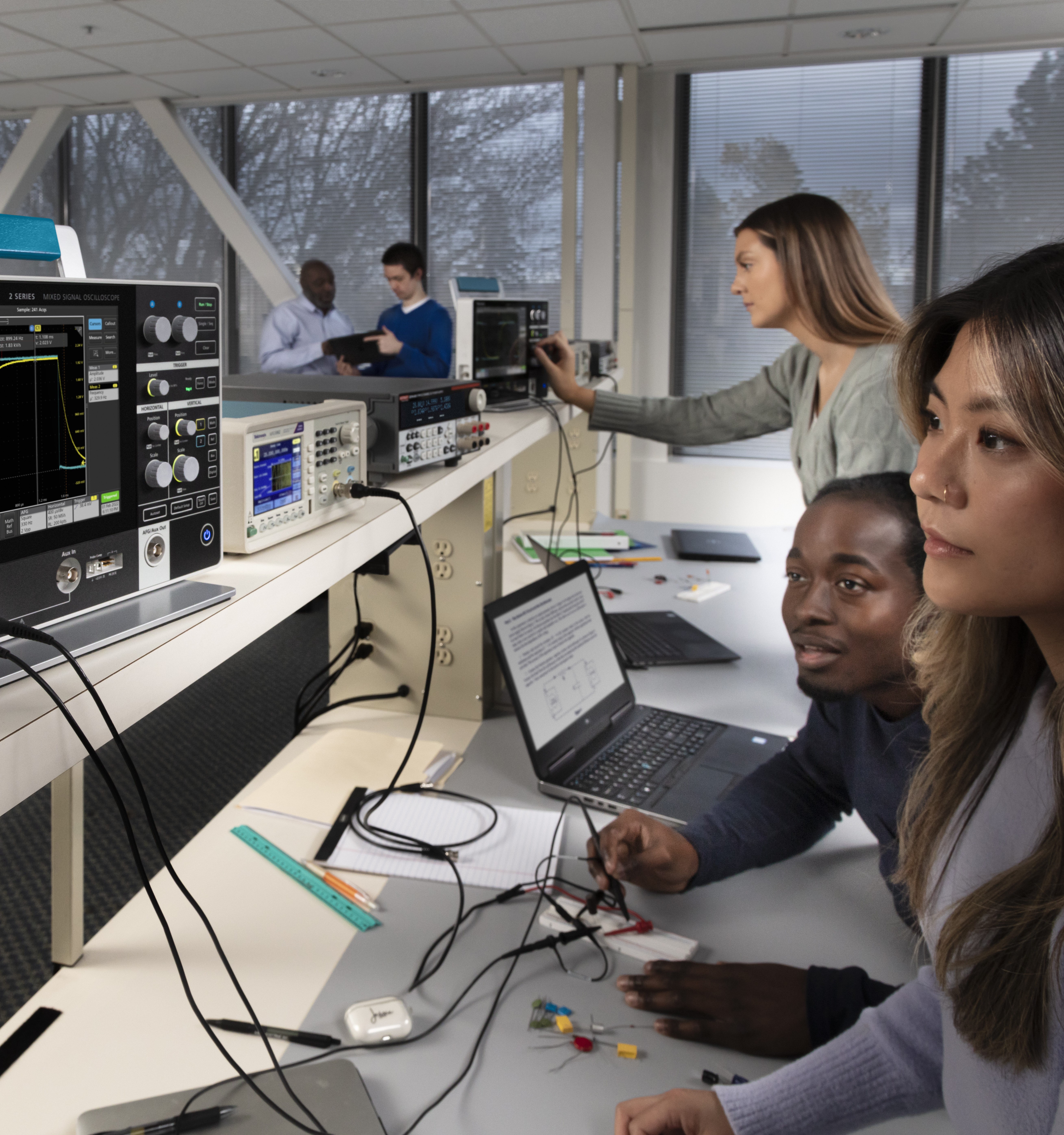 Group of engineers learning about and testing oscilloscope