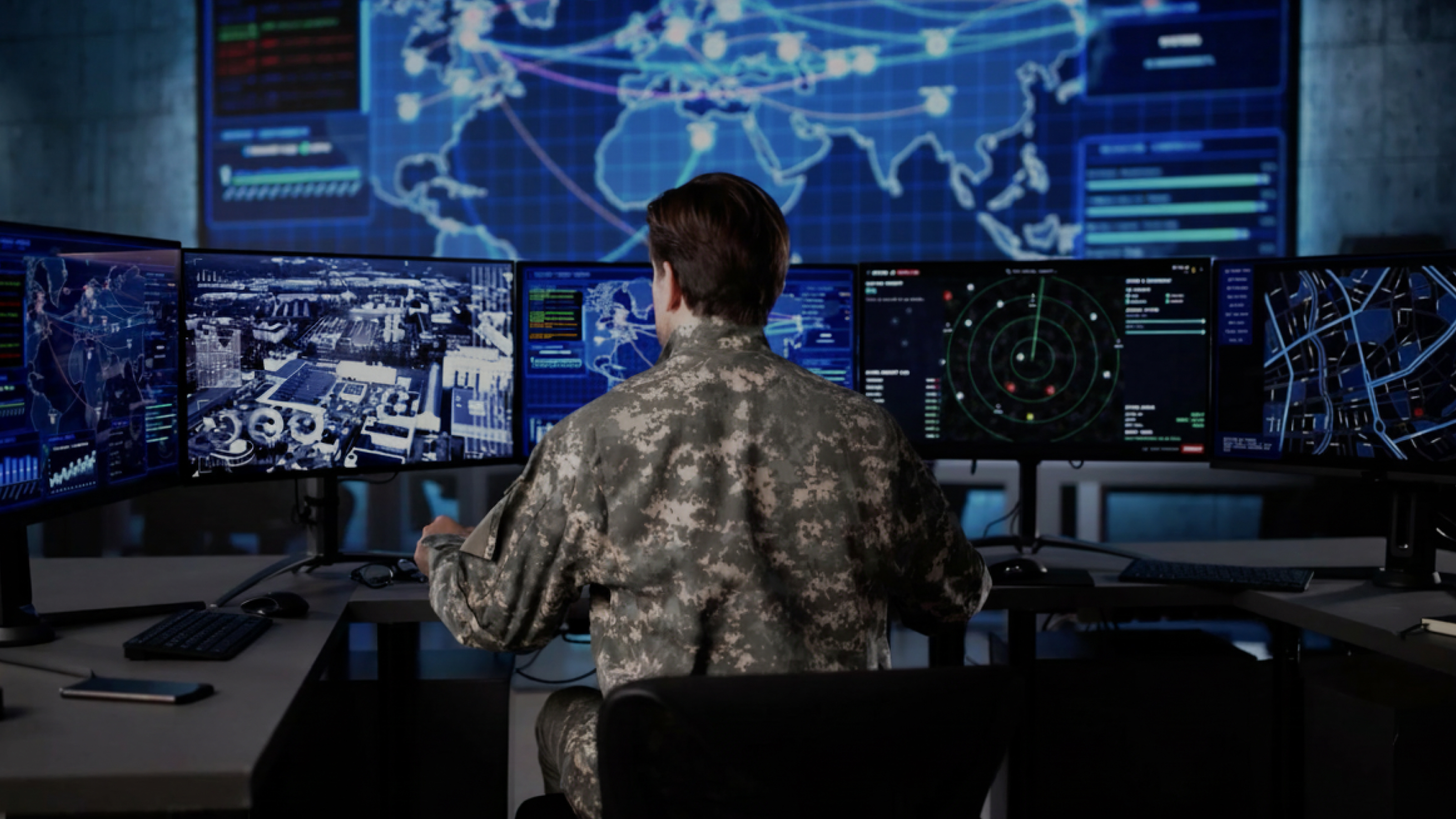 man in army fatigues sitting in front of a control board